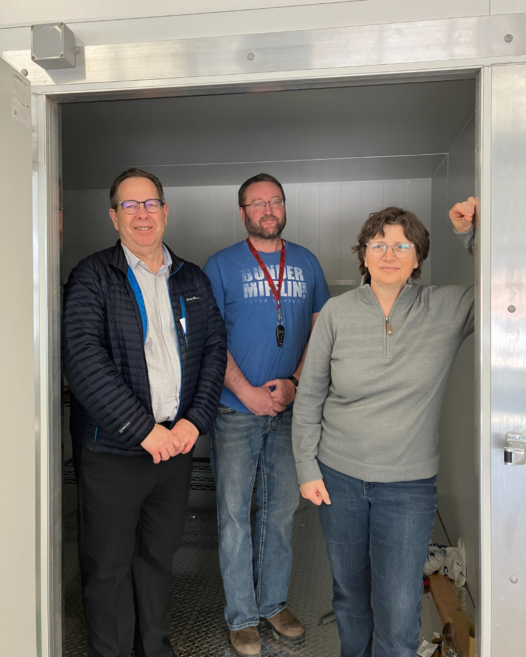 Left to right: Terry Erb (Paul and Ruby Erb Fund), Brian Bobette (General Manager of Manna Food Bank), Bonnie Paterson (Chair of Manna Food Bank) stand inside the new walk-in fridge and freezer at Manna Food Bank.